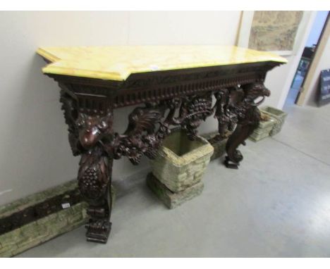 A carved mahogany console table with marble effect top.