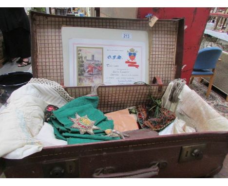 A vintage suitcase containing linen and a fraternal organisation sash
