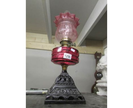 An oil lamp with cranberry shade and font