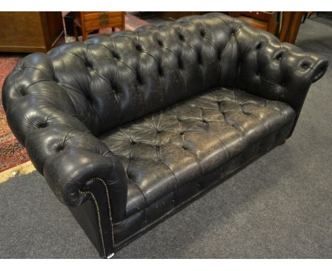 An office reception black two seat Chesterfield sofa.