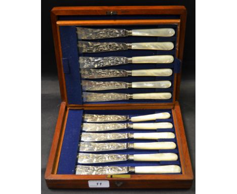 An oak case containing twelve mother of pearl hafted fish knifes by William Hutton & Sons, engraved with scrolling foliage