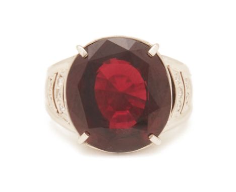 A GARNET AND DIAMOND RING
Set in platinum, the central garnet flanked by brilliant round cut diamond shoulders, 
The garnet w