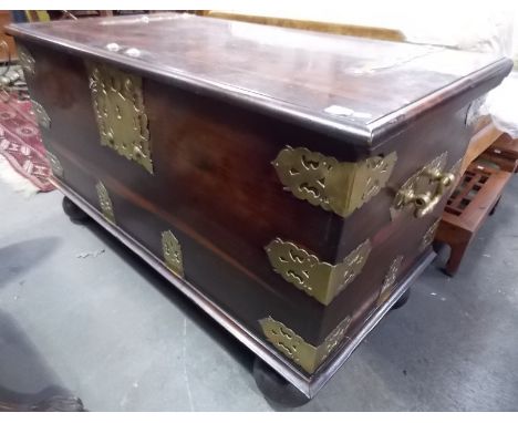 Large 20th Century Oriental hardwood brass bound trunk with side carrying handles, the hinged top with substantial lock, upon