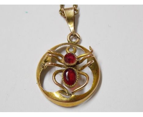 9ct spider pendant, the body set with a circular and oval ruby, 15mm diameter, upon a gold plated chain