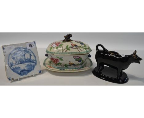 18th Century blue and white tin glazed tile painted with a church and landscape, together with a black glazed cow creamer and