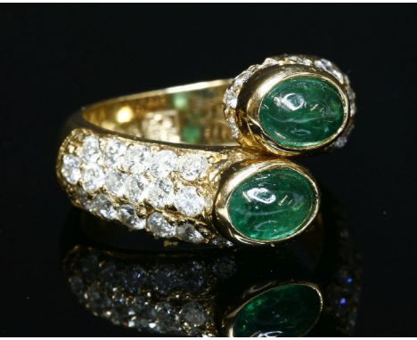 A Continental gold, emerald and diamond crossover ring, by Fitaihi, with two oval cabochon emeralds, rub set in a crossover p