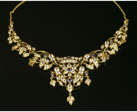 An Indian high carat gold, synthetic blue and white sapphire necklace, of open foliate form.  Graduated synthetic blue and wh