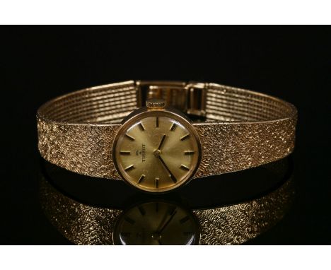 A ladies' 9ct gold Tissot mechanical bracelet watch, with a circular champagne dial, raised baton markers and an integral Mil