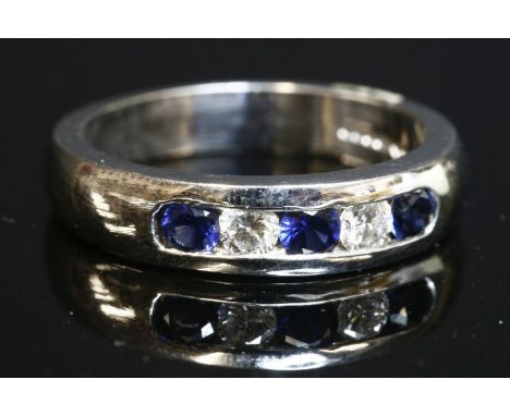 An 18ct white gold, sapphire and diamond one-third eternity ring, with a tapered 'D' section band, channel set with three cir