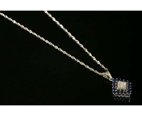 A white gold, diamond and sapphire, lozenge-shaped pendant, with nine princess cut diamonds, invisibly set to the centre.  A 