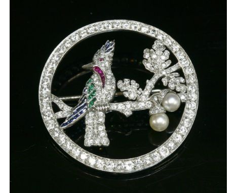 A platinum Art Deco, diamond, ruby, sapphire, emerald and cultured pearl bird brooch, c.1935,of hoop form.  The bird pavé set