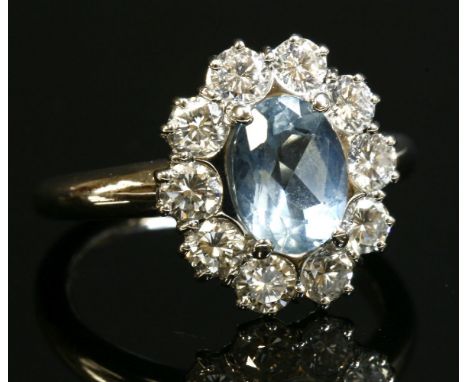 A white gold, aquamarine and diamond oval cluster ring,by Cellini, with an oval mixed cut aquamarine, four claw set to the ce