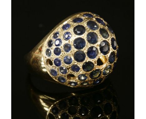 A Continental gold sapphire set bombé ring, with graduated circular mixed cut sapphires, pavé set to the head, four deficient