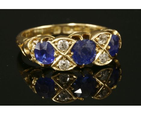 An 18ct gold Victorian sapphire and diamond carved head ring,with three circular old Swiss cut sapphires, claw set to a scall