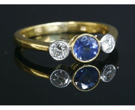 An 18ct gold, sapphire and diamond three stone ring, with a central circular mixed cut sapphire, with a stated weight of 0.67