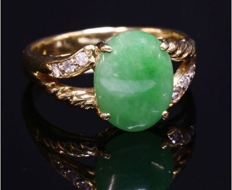 A Continental jade and diamond ring,with an oval jade cabochon, claw set to the centre.  Split shoulders with a row of three 