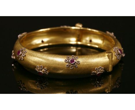 A Middle Eastern, ruby set, gold hinged bangle,of 'D' section form, with a series of circular faceted rubies, each one rub se