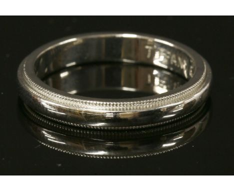 A platinum wedding ring by Tiffany, 'D' shaped, 3mm wide, with a fine milled edge.  Signed 'Tiffany &amp; Co.'. Marked PT950.