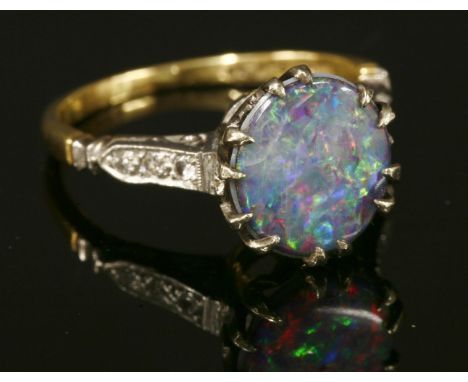 A single stone opal triplet ring, with diamond set shoulders, with an oval opal triplet, claw set to a pierced white collet, 