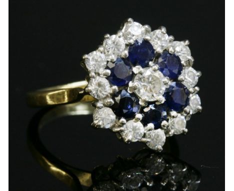 A diamond and sapphire three-tier cluster ring,with a brilliant cut diamond, claw set to the centre.  A border of circular mi