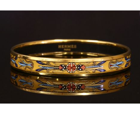 An Hermès narrow enamel printed bangle with gold-plated guards,ochre ground with a printed native American feather design.  S