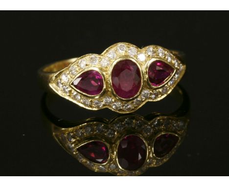 An 18ct gold, ruby and diamond regal cluster ring,with an oval mixed cut ruby, rub set to the centre.  A pear cut ruby, rub s