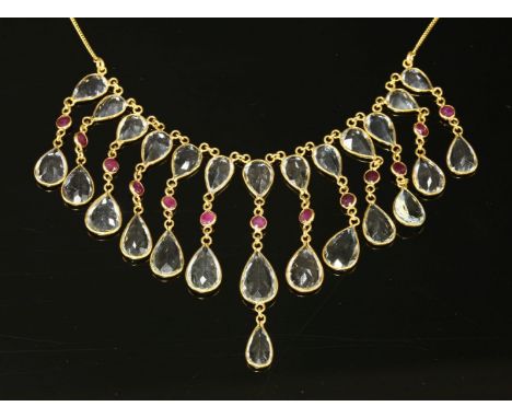 An aquamarine and ruby gold fringe necklace,with rows of pear cut aquamarines, spectacle set to each side of a circular caboc