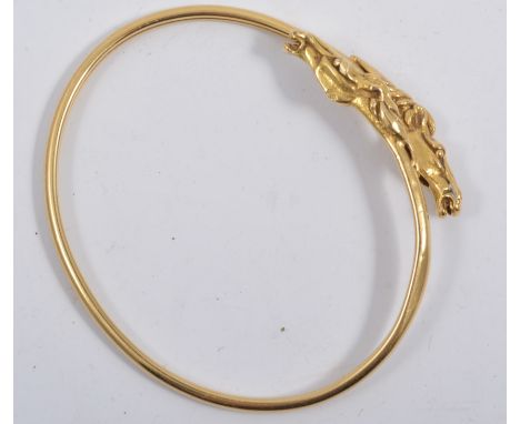 An 18 carat yellow gold 2.8mm wide sprung bangle, with horse head terminations, approximate weight 11.4gms.