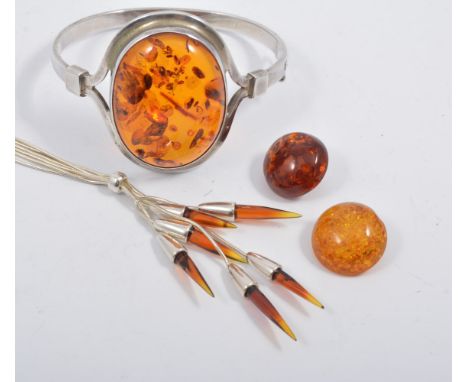 A hallmarked silver and Baltic amber bangle, the oval cabochon cut amber 40mm x 30mm, collet set to front of a 5mm wide half 