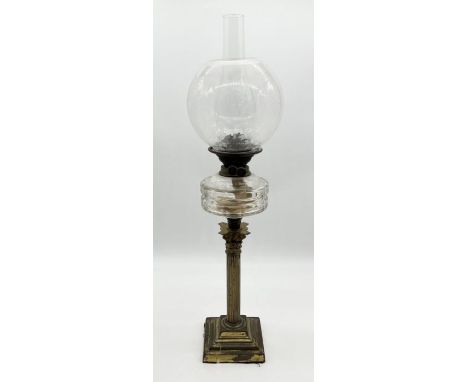 An antique oil lamp on brass column base with etched decoration to shade