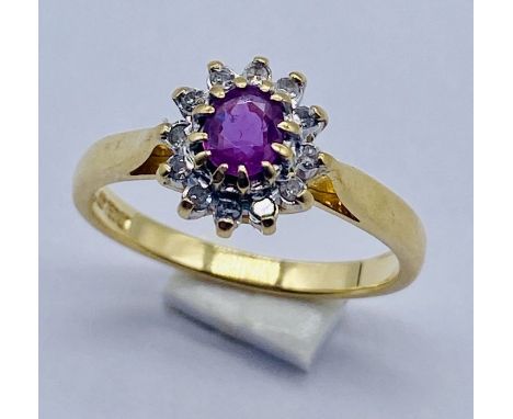 A ruby and diamond cluster ring set in 18ct gold