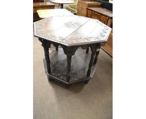 A late Victorian oak centre table of octagonal form with Gothic type carving, turned supports and a base shelf, 92cm wide