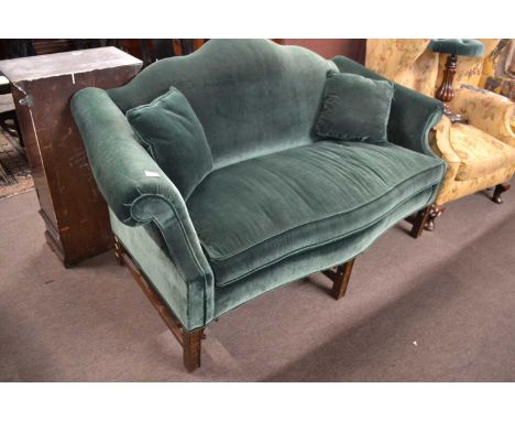 A Georgian style camel back sofa upholstered in green velvet with serpentine front and hardwood legs with blind fretwork deta
