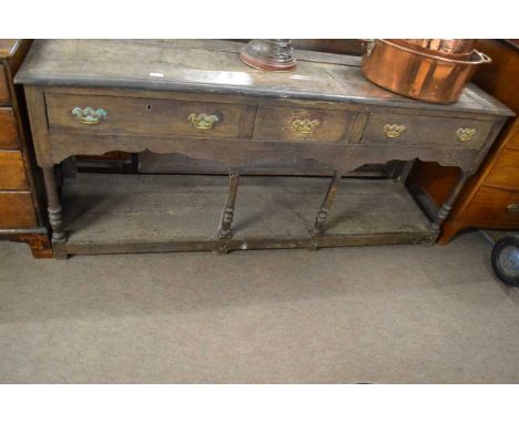 An 18th Century oak dresser base with three drawers, turned legs and a base shelf, distressed condition throughout, 181cm wid