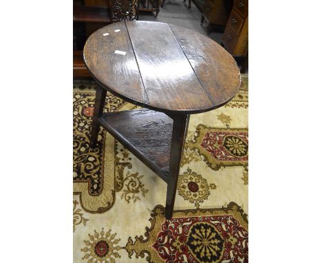 A Georgian oak and pine cricket table, the circular three plank top supported on three legs with a central shelf, 59cm diamet