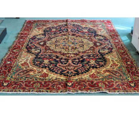 A Tabriz Carpet with a centre medallion surrounded by flowers on a blue field and floral border.  9' 4" (285cms) x 6' 5" (195