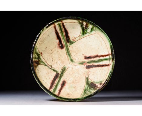 Ca. AD 900 - 1100A Nishapur glazed pottery bowl sitting upon an unglazed discoid foot with a deep basin, all enveloped in cre