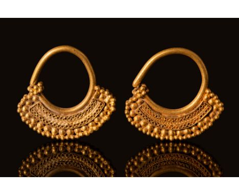 Ca. 300 - 100 BCA pair of Hellenistic gold earrings comprised of a thick tapering wire connected to an openwork large band de