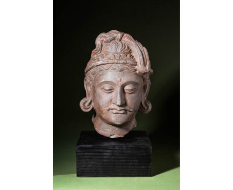 Ca. AD 30 - 375 A carved schist head of bodhisattva in the Kushan Empire style. The elaborately fashioned ushnisha has overfl