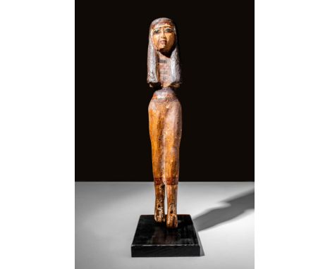 Late Period, Ca. 664 - 332 BCAn Egyptian wooden statuette of a woman depicted wearing a wig with a wreath of leaves and a lot
