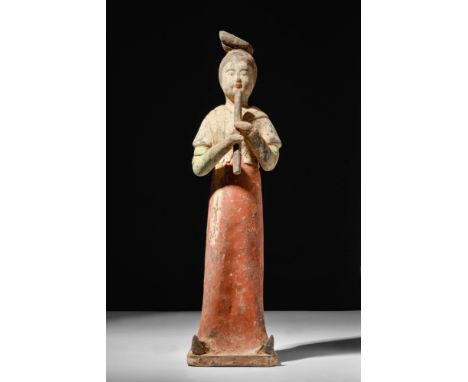 Ca. AD 618 – 907A Chinese terracotta female musician. The lady is standing upright, wearing a long robe beneath a short overt