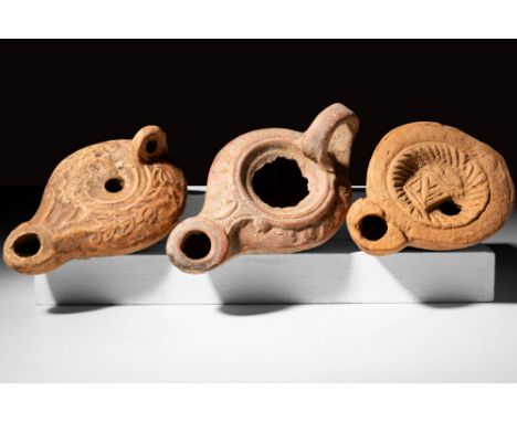 Ca. AD 50 - 200A set of three mould-formed Roman pottery oil lamps. The first lamp has a slightly depressed shoulder frame an