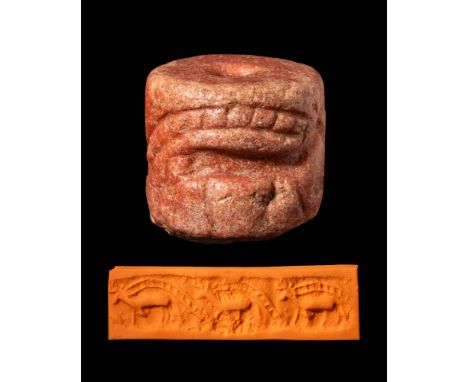 Ca. 3000 BCA Jemdet Nasr pink stone cylinder seal depicting two walking bulls. The bulls have a curving ladder pattern starti