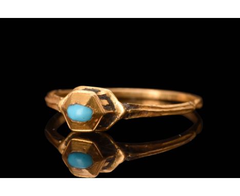 Ca. AD 1600A gold finger ring featuring a thin, round hoop with a median rib at the shoulders. The centerpiece of the ring is