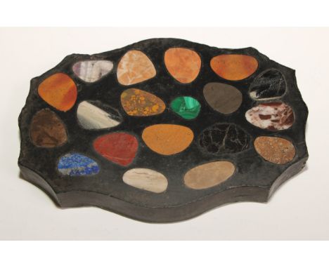 A pietra dura shaped serpentine desk weight, inlaid with pebble shaped reserves of malachite, laps lazuli, amethyst quartz an