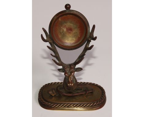 An early 20th century brass novelty combination pocket watch stand and pen rack, as a stag's head above ariding crop and fetl