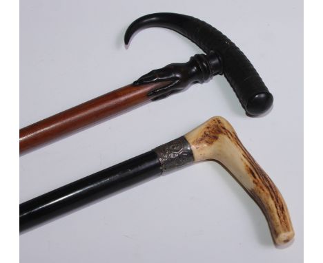 An early 20th century walking stick, the horn handle carved with a hand gripping the hardwood cane, 86cm long; another, stag 