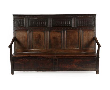 An Early 18th Century Joined Oak Settle, the back support with four carved panels with five moulded panels below, with downsw