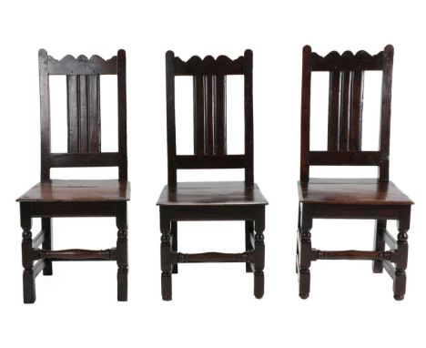 A Set of Three English Joined Oak Back Stools, circa 1700, each seat rail stamped EI, with wavy shaped top rails above moulde