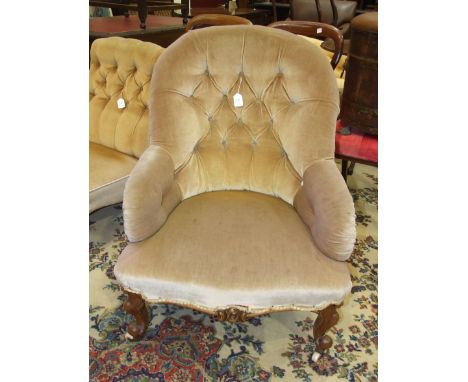 A Late-Victorian walnut upholstered button-back salon chair on carved cabriole front legs.